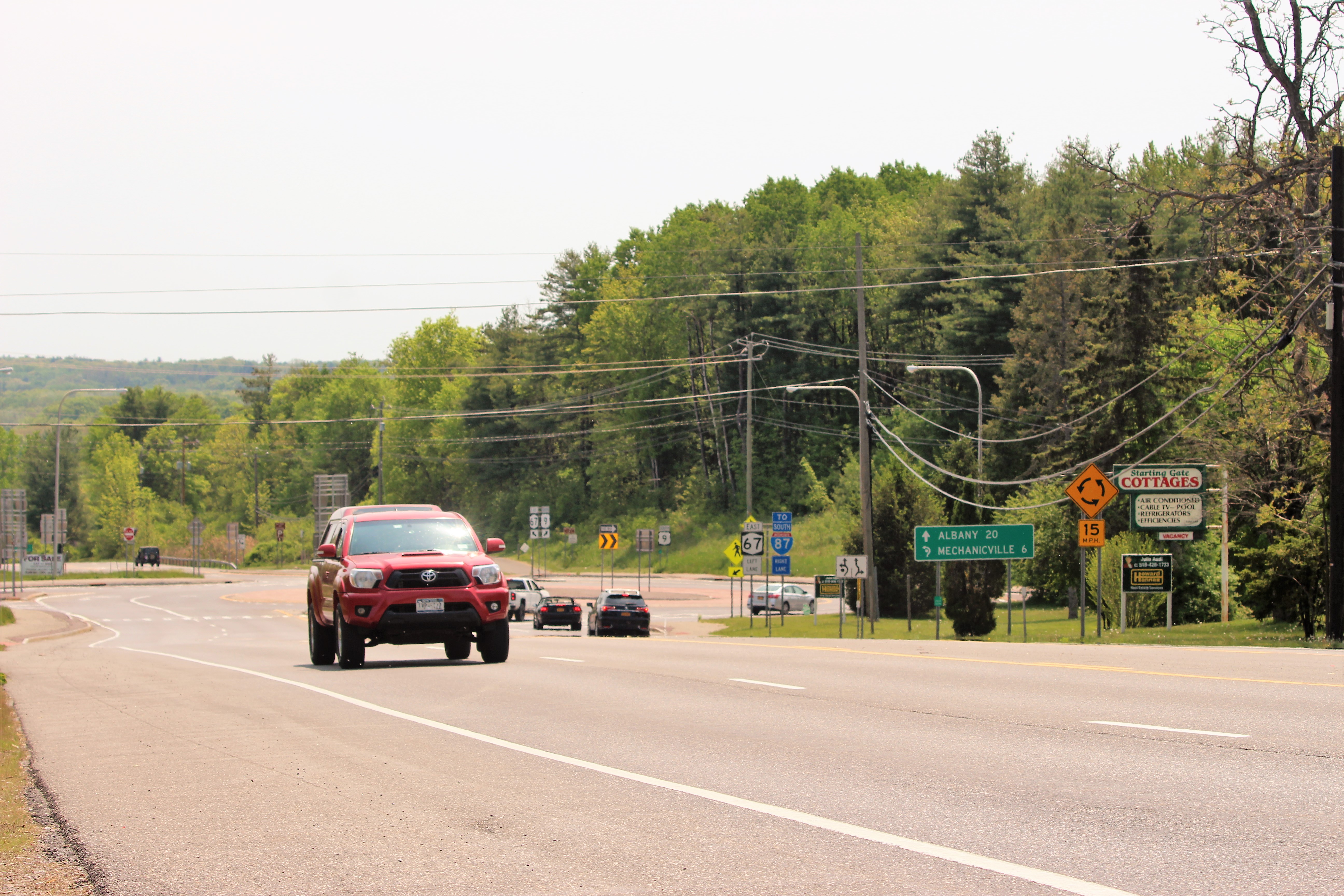 A roundabout along Route 9 in Malta, New York, with highway signage for Route 67 and I-87